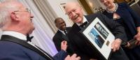 Bill Gies, II, shown at the 2017 William J. Gies Awards Gala, with framed prints of his grandfather and himself, side by side.